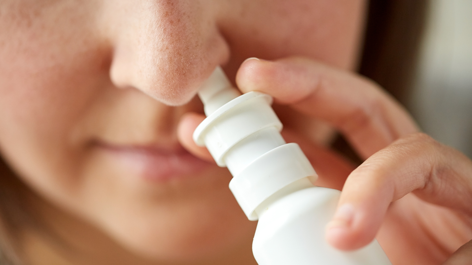 Woman using nasal spray for nasal disorder treatment